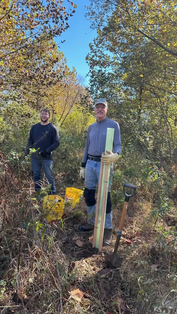 Volunteers with tree tubes and a shovel during tree planting at Longacres Farm