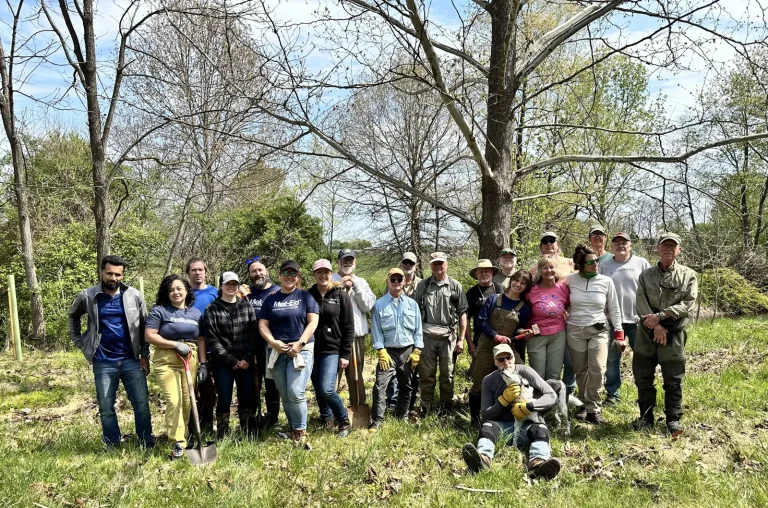 Group photo of tree maintenance volunteers with shovels in a wooded area – Longacres
